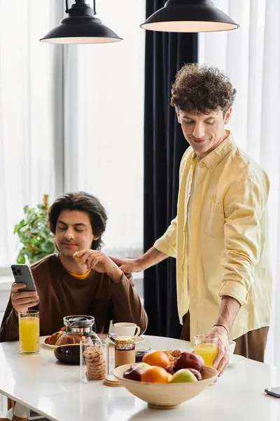 Gay couple enjoys a cozy morning together, sharing food and laughter in their beautiful modern space. — Stock Photo