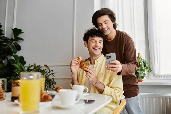 Двое мужчин делят восхитительный завтрак, улыбаясь и наслаждаясь компанией друг друга в их доме. — стоковое фото