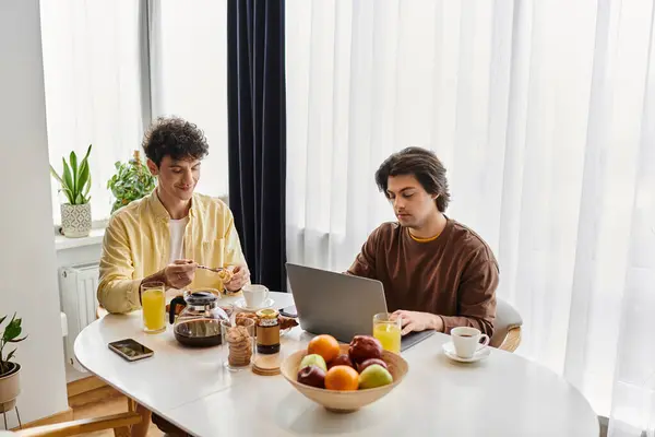 Two men share a cozy breakfast and work time in their bright, modern living space. — Stock Photo