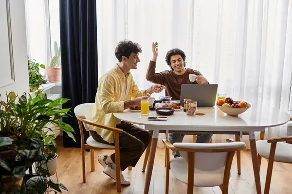 Due uomini si godono una mattinata gioiosa insieme, condividendo la colazione e sorridendo nella loro elegante casa. — Foto stock