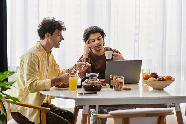 Two good-looking men enjoy breakfast and engage in conversation at their modern dining table. — Stock Photo
