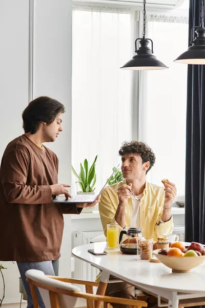 Two men enjoy a cozy breakfast together in a stylish apartment filled with plants. — Stock Photo