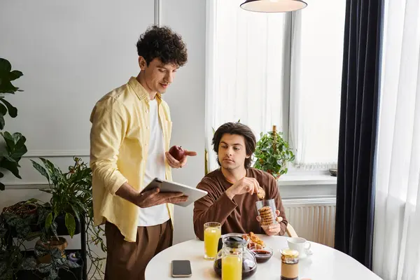 Two men share breakfast and laughter in their stylish apartment. — Stock Photo