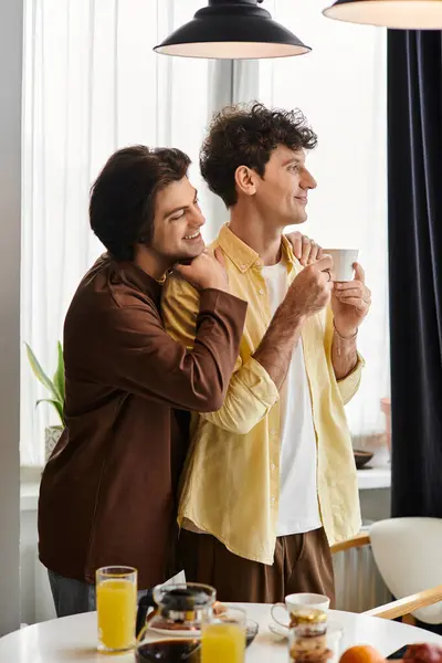 Gay couple embrasse heureux dans leur élégant appartement tout en appréciant le petit déjeuner ensemble. — Photo de stock