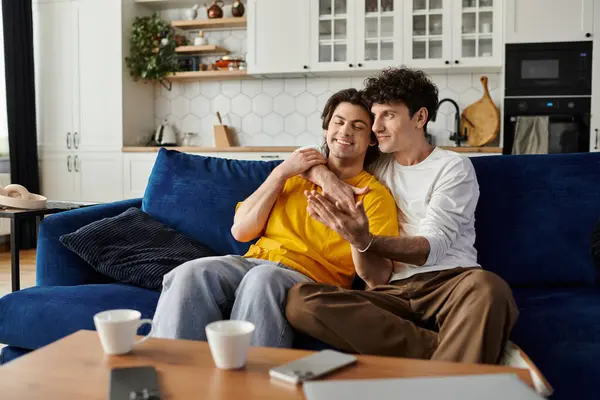Two handsome men share a tender moment in their stylish apartment while relaxing together. — Stock Photo