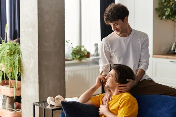A lovely gay couple shares a tender moment while relaxing in their stylish apartment, celebrating love. — Stock Photo