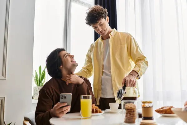 A loving gay couple enjoys a cozy breakfast in their modern apartment filled with sunlight. — Stock Photo