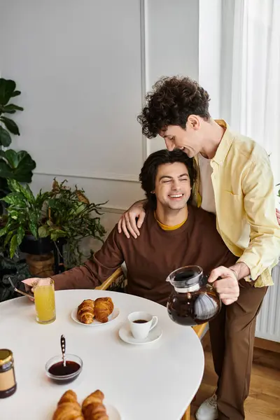 Two good-looking men enjoy breakfast together in a stylish apartment filled with plants. — Stock Photo