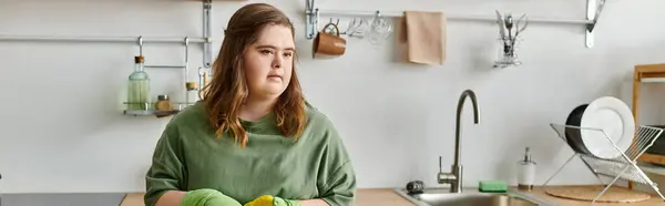 Una joven con síndrome de Down se encuentra en su cálida cocina, irradiando confianza y comodidad. - foto de stock
