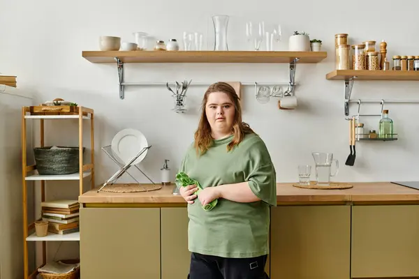 In a cozy kitchen, a young woman with Down syndrome stands confidently, holding fresh vegetables. — Stock Photo