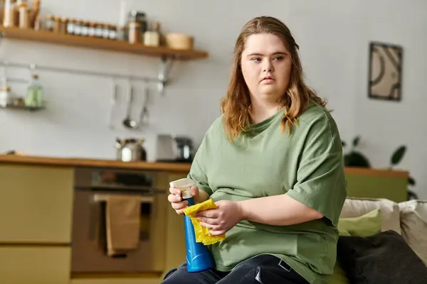 Una joven con síndrome de Down limpia felizmente su acogedora casa. - foto de stock