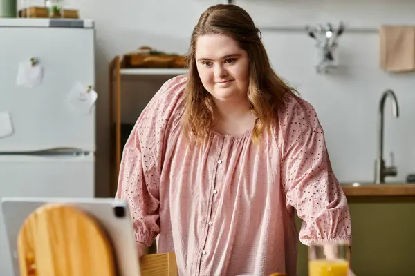 Bright and cheerful young woman with Down syndrome engages in a delightful online chat at home. — Stock Photo