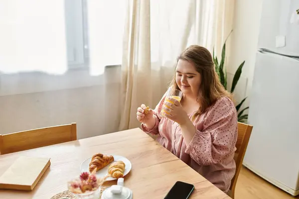 A young pretty woman with Down syndrome savors a morning drink at a cozy breakfast table. — Stock Photo
