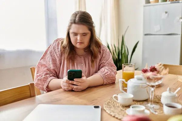In a cozy home, a young woman with Down syndrome feels confident while using her phone. — Stock Photo