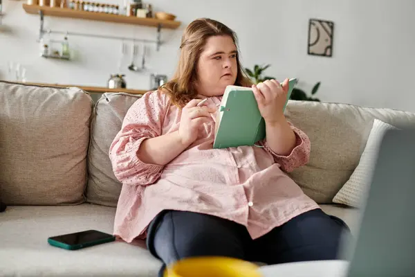 A young woman with Down syndrome showcases her creativity while relaxing at home with a notebook. — Stock Photo