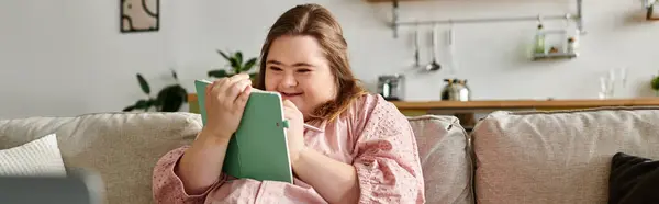 A young woman with Down syndrome enjoys some cozy time with her notebook at home. — Stock Photo