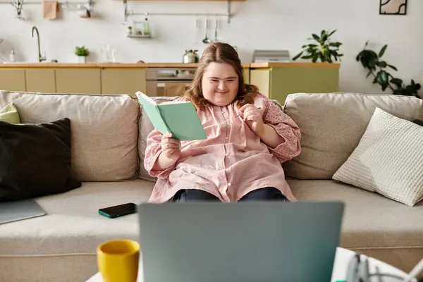 In a cozy home, a young woman reads joyfully, exuding comfort and confidence. — Stock Photo
