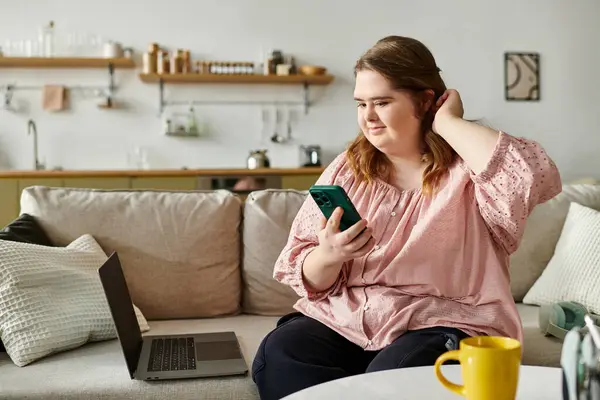 Una giovane donna con la sindrome di Down si rilassa a casa, usando con fiducia il suo telefono e laptop. — Stock Photo