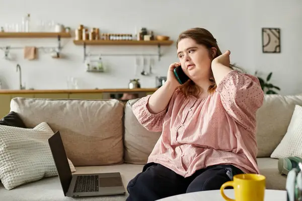 Young woman with Down syndrome relaxes at home, engaged in a conversation while seated comfortably. — Stock Photo