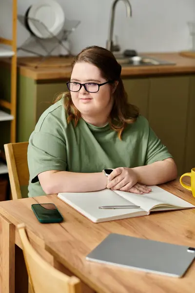 Young woman with Down syndrome studies comfortably at her table while relaxing at home. — Stock Photo