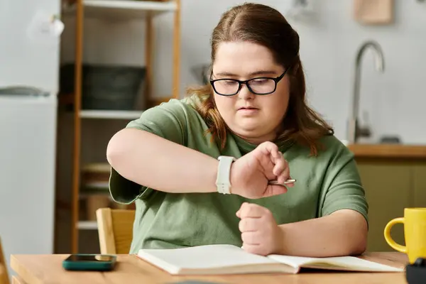 A young woman with Down syndrome focuses on her notebook while relaxed in a comfy home setting. — Stock Photo