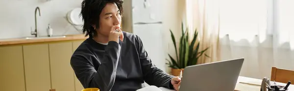 A handsome young asian student concentrates on his laptop while studying at home, banner — Stock Photo