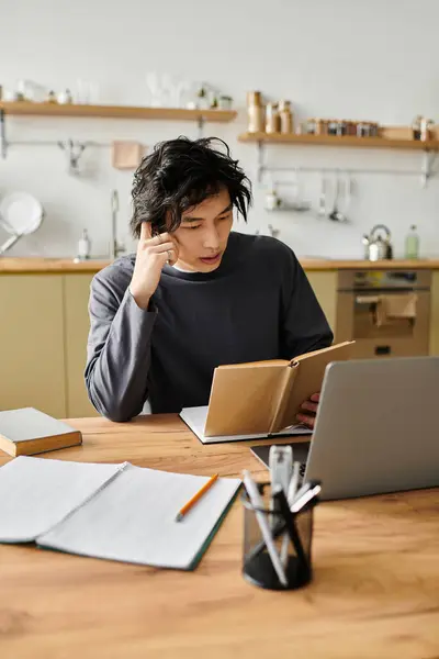A handsome asian student focuses on his studies at home, exploring online learning materials. — Stock Photo