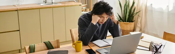 A focused young man studies online from his home, immersed in learning while managing distractions, banner — Stock Photo