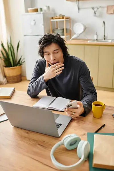 Tired young Asian man sits at a wooden table, tired from studying online at home. — Stock Photo