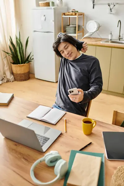 Handsome young man stretches while studying online at home, balancing relaxation and education. — Stock Photo