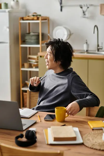 Handsome young Asian student engaged in online studies at his cozy home workspace. — Stock Photo