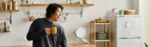 A handsome young student engages in e-learning at home while sipping a warm drink, banner — Stock Photo