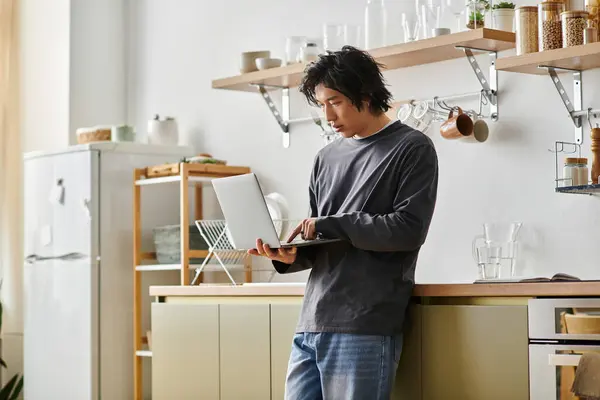 A young Asian student concentrates on his laptop, enjoying online education from home. — Stock Photo