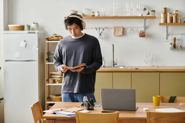 Focused young man studies intently while standing in his bright, modern kitchen at home. — Stock Photo