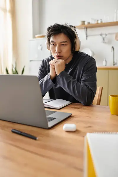 A handsome young student studies intently at home using his laptop for online education. — Stock Photo