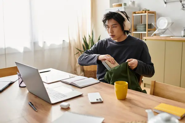 A young man concentrates on his online class while preparing his materials at home. — Stock Photo