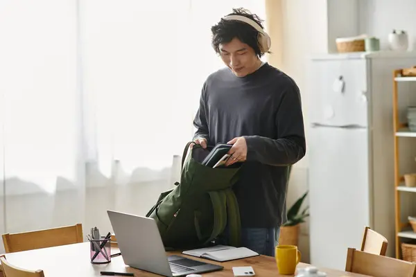 Young man prepares his study materials while attending an online class at home. — Stock Photo