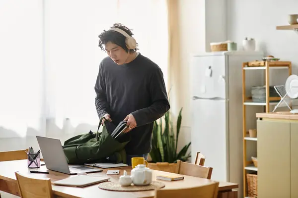 Handsome young man zips up his bag while getting ready for online classes at home. — Stock Photo