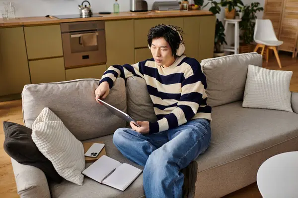 Handsome young man focused on his studies, using a laptop while seated on a comfortable couch. — Stock Photo