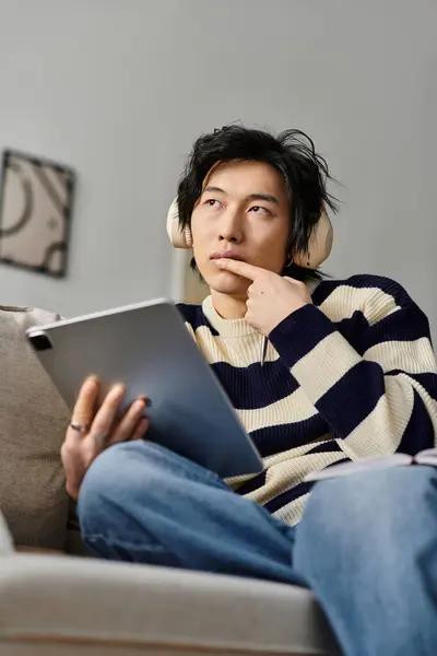 A young student studies attentively using a tablet while relaxing at home, immersed in learning. — Stock Photo