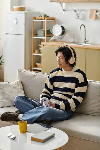 Young man relaxes in a stylish living room, listening music in headphones — Stock Photo