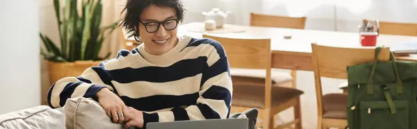 A focused student enjoys his online learning experience while sitting on a couch at home, banner — Stock Photo