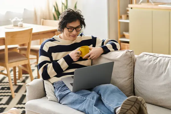 A young asian student engages in e-learning from the comfort of home while sipping coffee. — Stock Photo