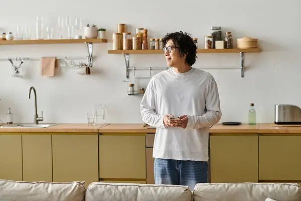 A handsome young Asian man stands thoughtfully in a stylish home, looking relaxed and comfortable. — Stock Photo