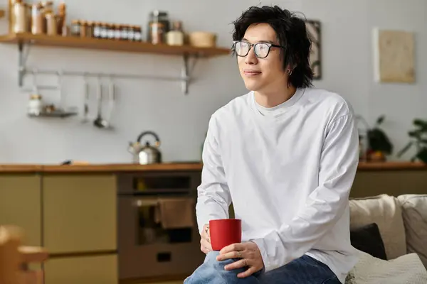 A handsome young man smiles while sipping coffee in his stylish urban home this morning. — Stock Photo