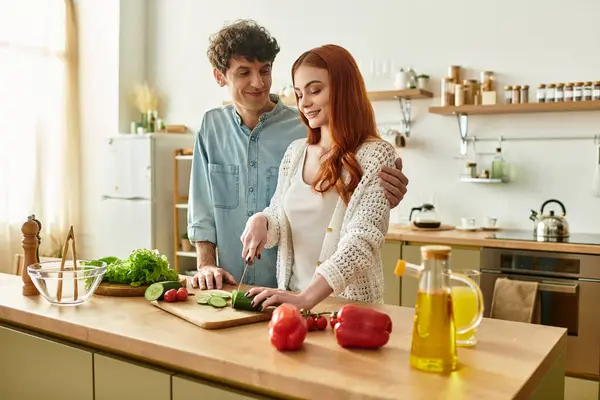 Casal jovem compartilha momentos íntimos enquanto prepara uma refeição em sua cozinha quente e convidativa. — Fotografia de Stock