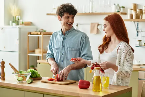 Young couple enjoys quality time in their kitchen, chopping vegetables and sharing laughter. — Stock Photo