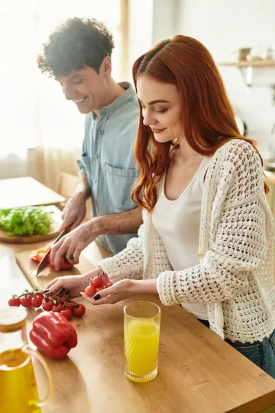 A young couple enjoys quality time together preparing a meal in their warm, inviting kitchen. — Stock Photo
