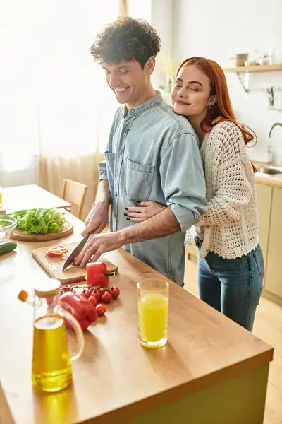 Joyful moments unfold as a young couple shares intimate time cooking in their warm kitchen. — Stock Photo