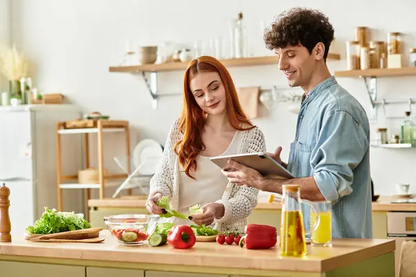 A young couple enjoys each others company while preparing a meal in their cozy kitchen. — Stock Photo